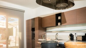 A modern kitchen with a central island, stainless steel range hood, and a sliding glass door leading to an outdoor area.