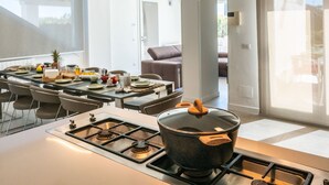 A modern kitchen with a gas stove, a large pot on the stove, and a dining area with a table set for a meal.