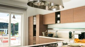 A modern kitchen with a central island, stainless steel appliances, and a large window overlooking a patio area.