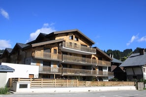 Un immeuble à plusieurs étages doté de balcons, qui ressemble probablement à un hôtel ou à un complexe touristique, avec un ciel bleu clair en arrière-plan.