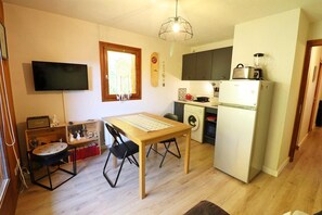 Un espace de vie compact comprenant un coin repas, un lave-linge et un réfrigérateur.