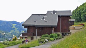 A modern two-story building with a sloped roof, situated on a hillside with a view of a valley. - Balcony, 28m², Les Gets (Les Gets)