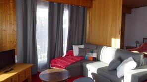 A cozy living room with a sofa, a television, and a wooden table.