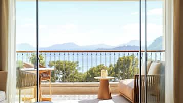 Un balcón con vista al mar y a las montañas, amoblado con un sofá, una silla y una mesa.