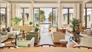 Amplia sala de estar con diversas opciones de asiento, ventanas amplias que ofrecen vistas al exterior y un camino central.