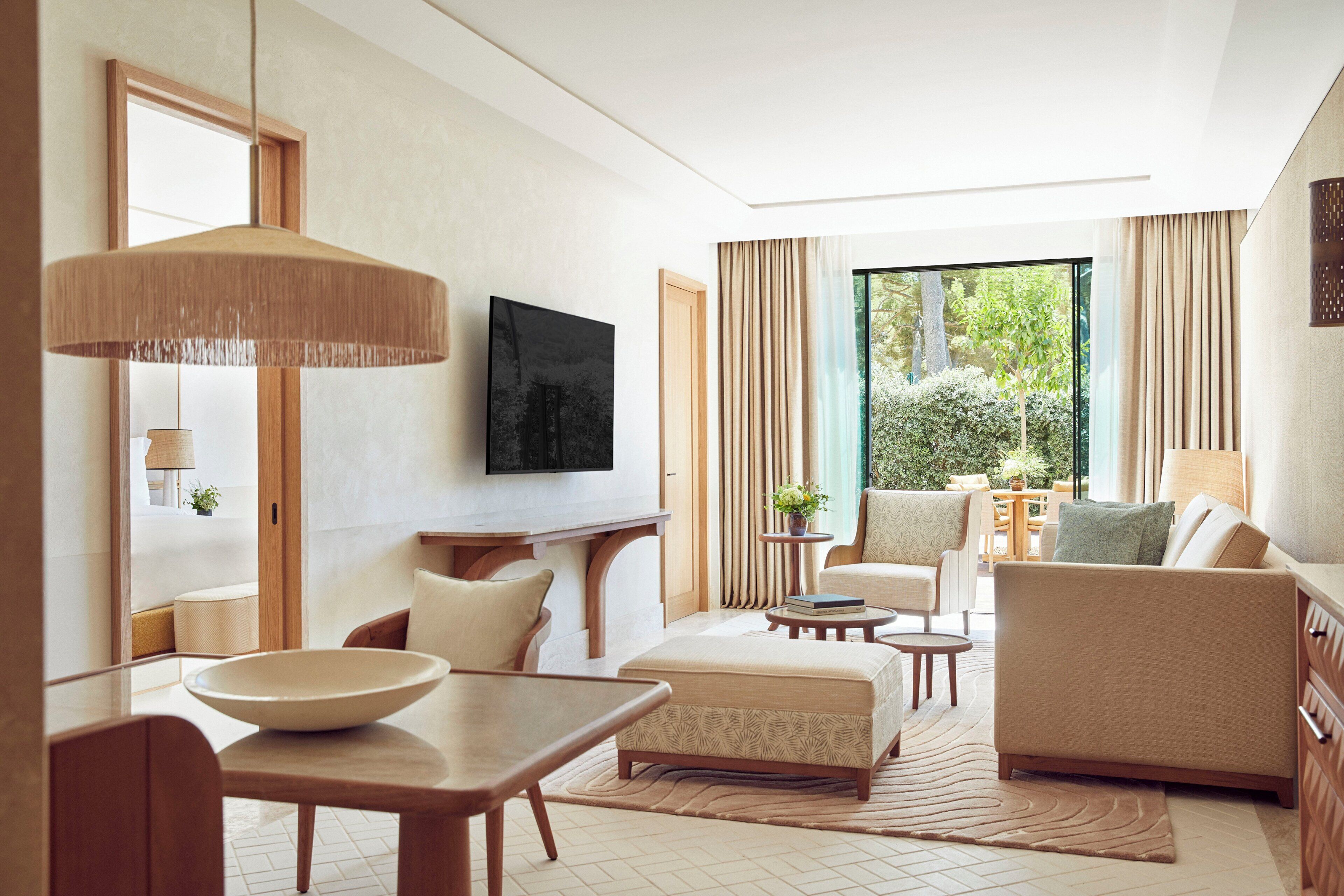Ein modernes Wohnzimmer mit großem Fenster, Flachbildfernseher, Esstisch mit Schüssel und einer Couch.