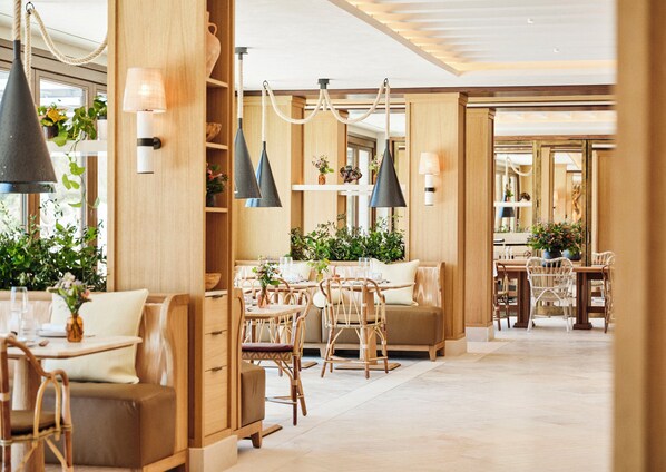 Un moderno vestíbulo de hotel con muebles de madera, lámparas colgantes y plantas en macetas.
