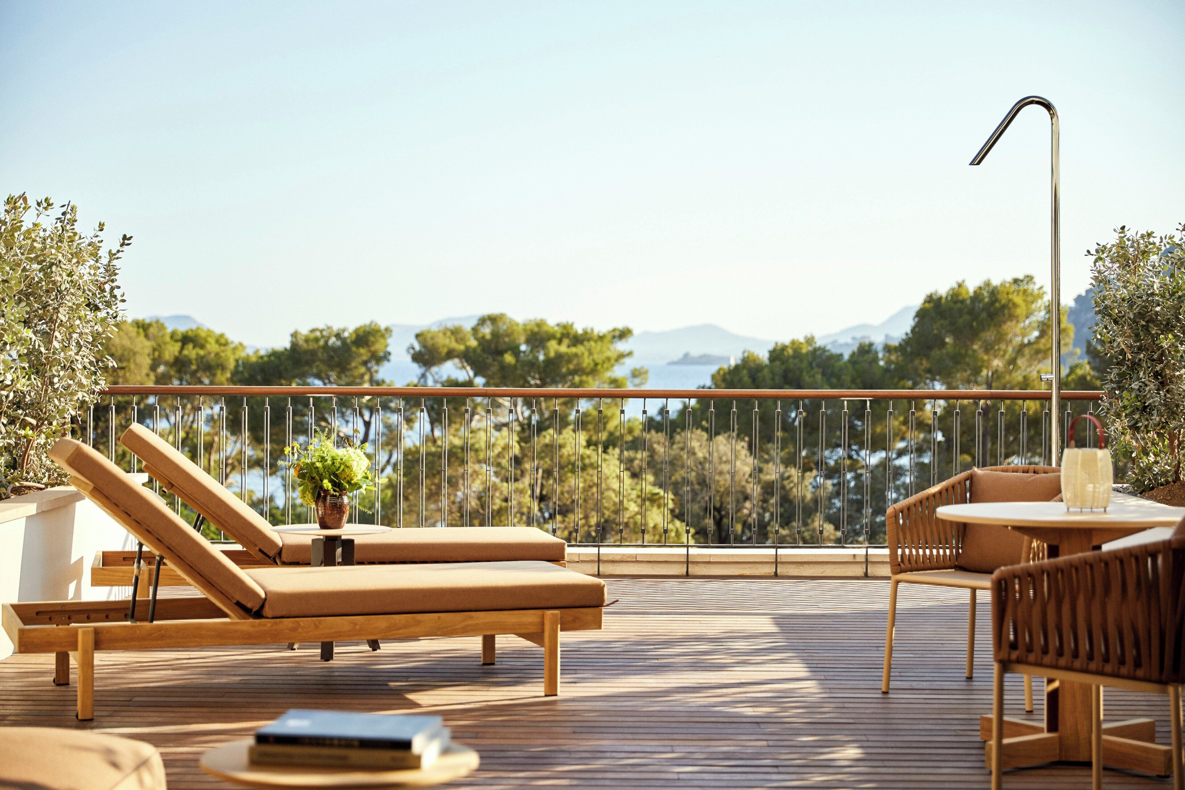 Una terraza de madera con una tumbona, una mesa y una silla.