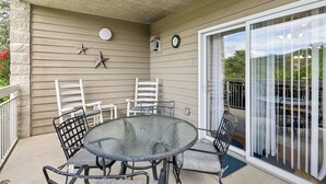 A covered patio area with a round glass table and four chairs, a clock, and a star decoration on the wall. - 3 BR | Indoor Pool/Hot Tub | Balcony | Free Tickets (Pigeon Forge)