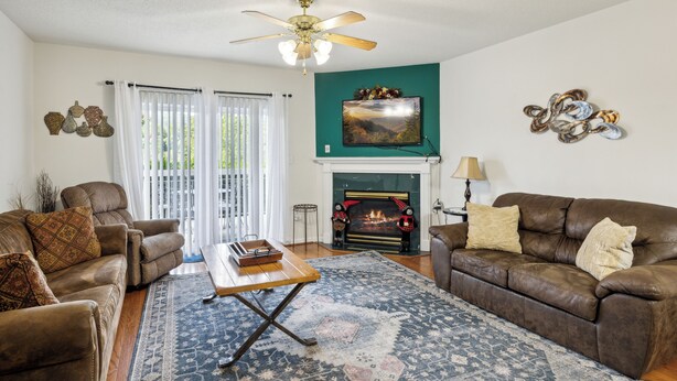 A living room with a fireplace, two sofas, a coffee table, and a ceiling fan. - 3 BR | Indoor Pool/Hot Tub | Balcony | Free Tickets (Pigeon Forge)