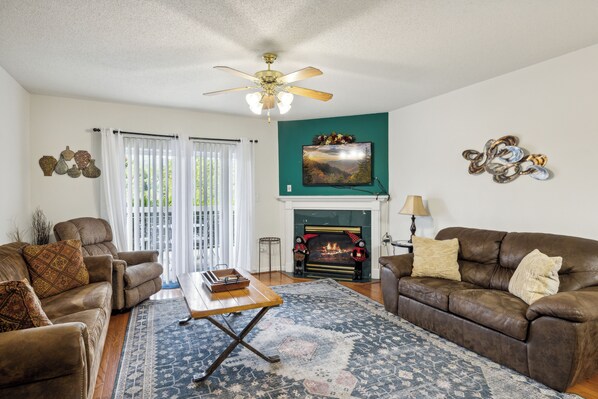 A living room with a fireplace, two sofas, a coffee table, and a ceiling fan.