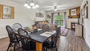 Un coin repas avec une table et des chaises en bois, un ventilateur de plafond et une cheminée.
