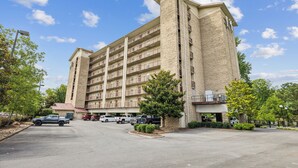 A multi-story hotel with a central courtyard, parking area, and a pedestrian bridge. - Stay on the River, Steps from Dolly Parton’s Stampede – Charming 2BR Retreat (Pigeon Forge)