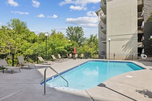 A swimming pool with lounge chairs and a building in the background.
