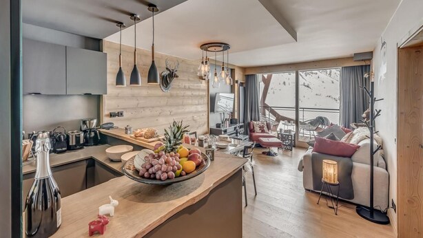 A modern kitchen with a central island, a dining area with a sofa and a coffee table, and a large window offering a view of a snowy landscape. - 200m from ski slopes, 5th floor, view mountain, balcony, ski locker, 50m², Tignes (Tignes)