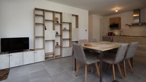 Une cuisine moderne avec un coin repas, un téléviseur et des étagères intégrées.