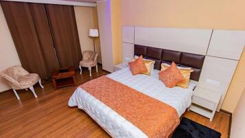 Una habitación de hotel con una cama grande, una mesita de noche, una silla y una lámpara.