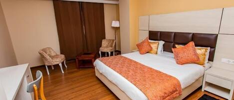Una habitación de hotel con una cama grande, un escritorio, dos sillas y un armario.
