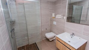 A modern bathroom with a glass-enclosed shower, a white sink, and a wooden vanity. - Royal Elisa Annaba (Annaba)