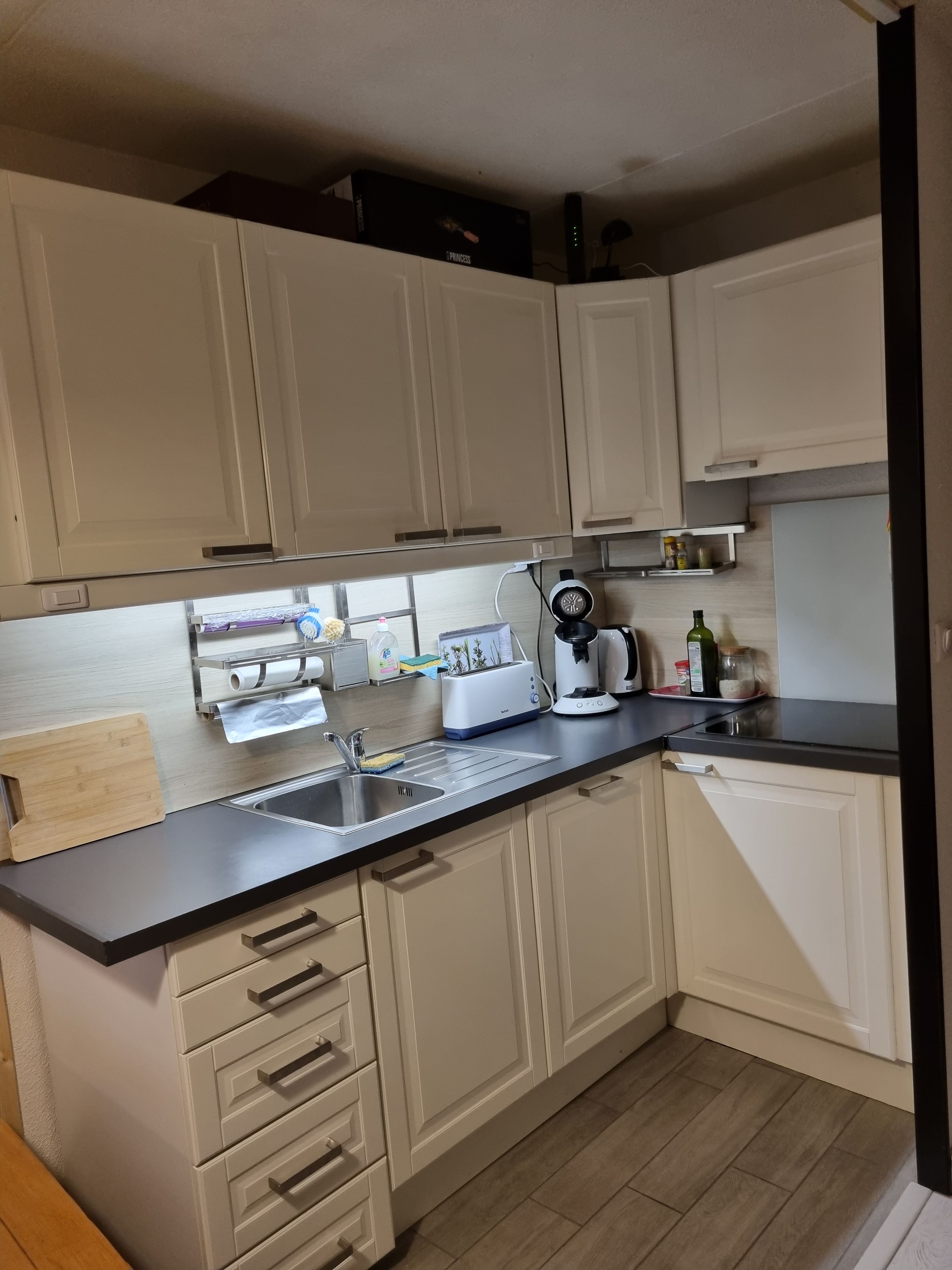 A kitchen with white cabinets, a black countertop, a toaster, a coffee maker, and a sink.