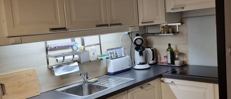 A kitchen with white cabinets, a black countertop, a toaster, a coffee maker, and a sink.