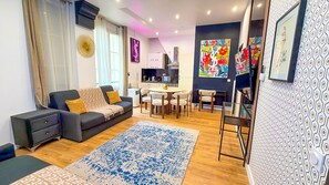 A modern living room with a sofa, a coffee table, and a dining area with chairs. - Urban Flat 156 - Yves Flat in Montorgueil (París)