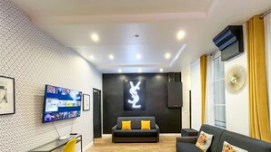 A modern living room with a black sofa, a TV mounted on the wall, and a neon sign. - Urban Flat 156 - Yves Flat in Montorgueil (París)