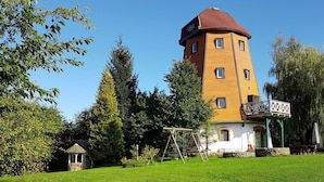 Ein mehrstöckiges Gebäude mit einem Turm, umgeben von einer gepflegten Rasenfläche und Bäumen.