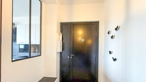 A hallway with a bench, a door with a QR code, and a wall-mounted light fixture.