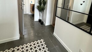 A hallway with a patterned rug, a potted plant, and a large mirror on the wall.