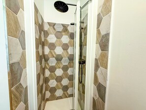 A shower area with hexagonal patterned tiles and a handheld showerhead.