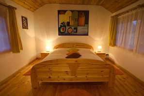 A wooden bed in a room with a painting on the wall, two bedside lamps, and curtains on the windows. - Apartment in Masuria with Private Pond (Gizycko)