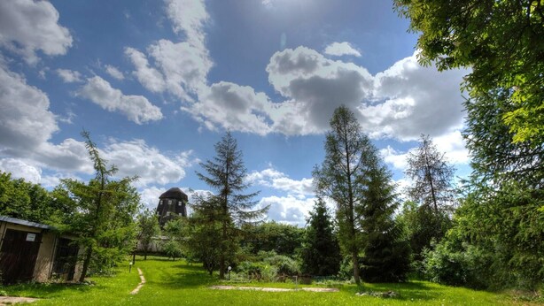 Un paysage verdoyant et luxuriant, avec un ciel dégagé, un petit bâtiment et une tour en arrière-plan.