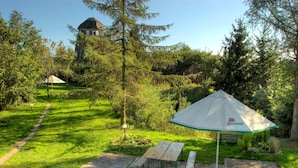 Un jardin avec une table de pique-nique et un parasol, un chemin de pierres et un bâtiment en arrière-plan.