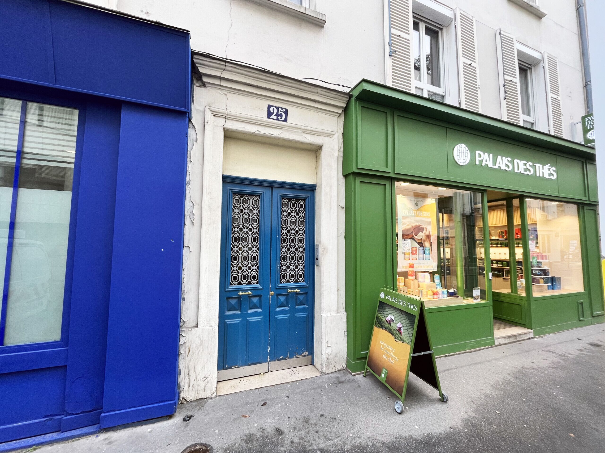 A storefront with a green facade, a blue door, and a sign reading "PALAI DES THÈS".
