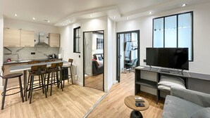 A modern apartment with a kitchen, dining area, living room, and a TV. - Urban Flat 173 - Atelier Gaite Montparnasse Apartment (París)