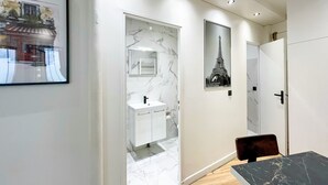 A modern bathroom with a marble sink, a mirror, and a framed picture of the Eiffel Tower. - Urban Flat 173 - Atelier Gaite Montparnasse Apartment (París)