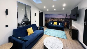 Una sala de estar moderna con dos sofás, una mesa de centro y un mural grande de un paisaje urbano.