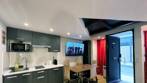 Eine moderne Küche mit Einbau-Mikrowelle, einem Esstisch mit Stühlen und einem an der Wand befestigten Fernseher, der eine Fernsehsendung zeigt.