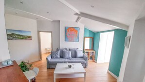 Uma sala de estar moderna com sofá cinza, mesa de centro branca e uma parede de destaque em tom verde-água.
