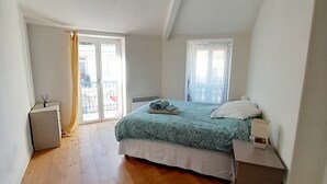 Quarto com cama, mesa de cabeceira, escrivaninha, luminária, janela e porta.