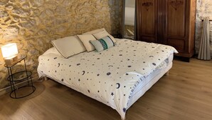 Makuuhuone, jossa on kiviseinä, puinen vaatekaappi ja tähtitaivaalla kuvioitu sänky.