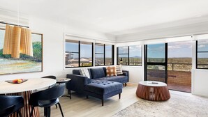Un grand espace de vie comprenant une grande fenêtre, un canapé, une table à manger et une table basse.