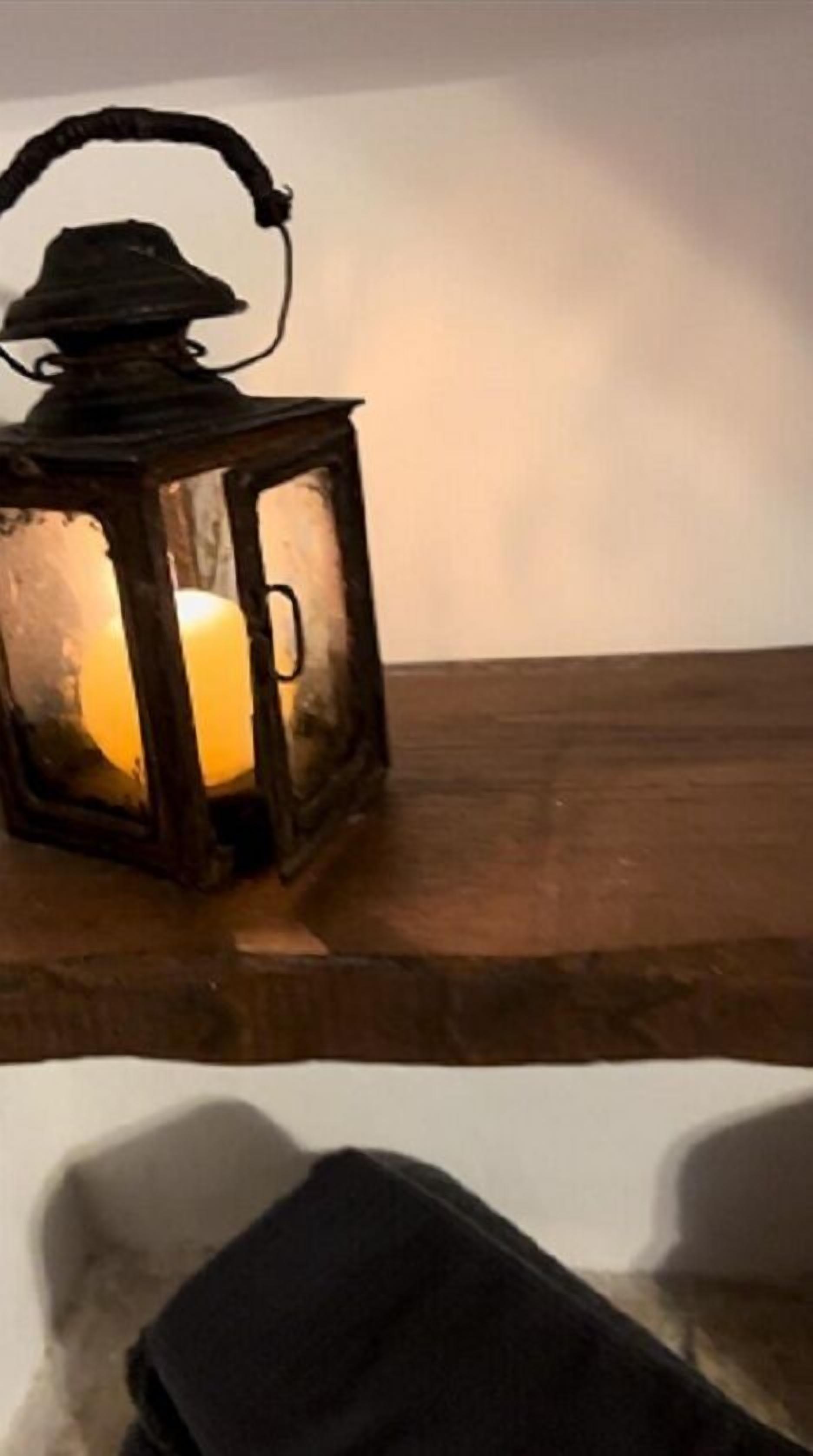 Ein Holztisch mit einer beleuchteten Laterne und einer schwarzen Tasche darauf.