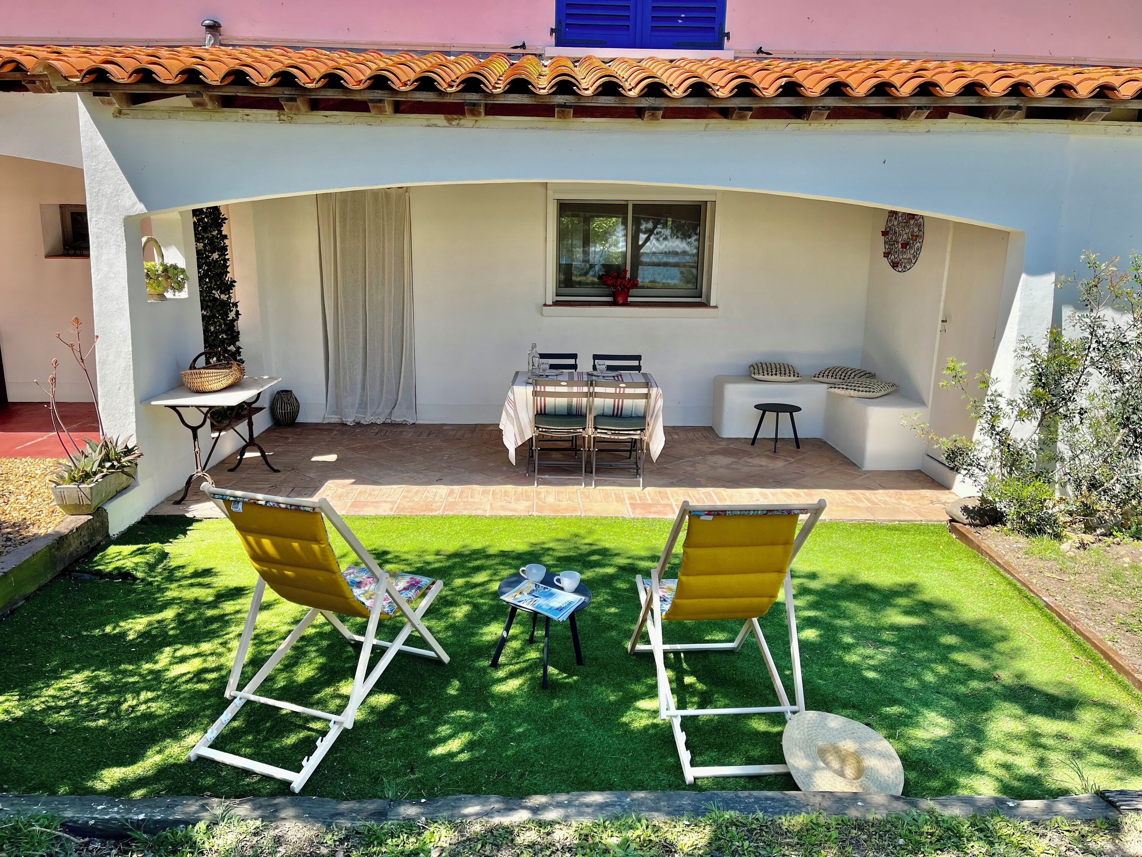 Une terrasse avec une table et des chaises, une petite table avec un panier, et une chaise jaune.
