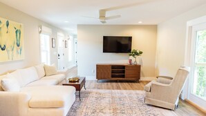 A modern living room with a sectional sofa, a recliner, a wooden entertainment unit, and a flat-screen TV. - Mammoth Cave, WKU, Barren River Lake, Travel Sports, Corvette (Bowling Green)