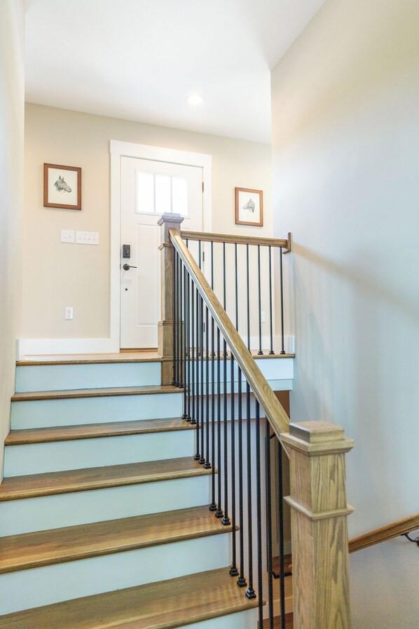 A staircase with wooden steps and black railings, leading to a white door with a small picture frame above it.
