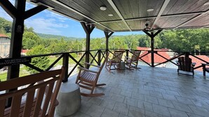 A covered outdoor seating area with wooden chairs and tables, overlooking a scenic landscape. - Helen Studio Living Suite 102 (Helen)