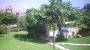 A residential area with a well-maintained lawn, palm trees, and a parked car. - Casa Clarita top Location for Your Cancun Experience (Cancún)