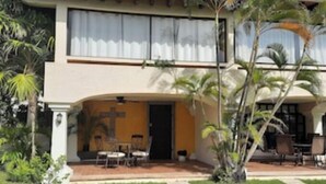 A two-story building with a patio area, outdoor seating, and a cross mural on the wall. - Casa Clarita top Location for Your Cancun Experience (Cancún)